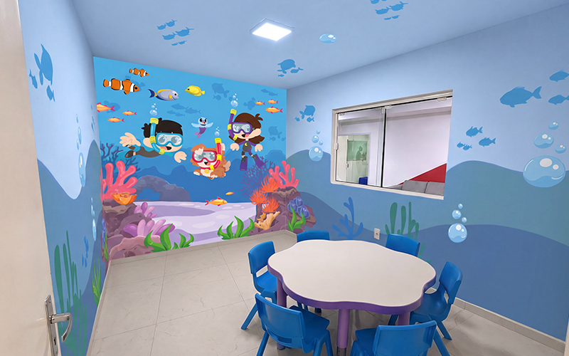 Sala Oceano da Knowa com decoração submarina, mesas infantis e personagens mergulhadores